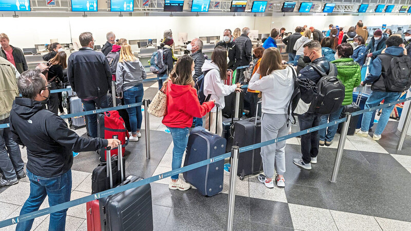 Flugpassagiere warten am Freitag an einem Check-in-Schalter des Flughafen München.