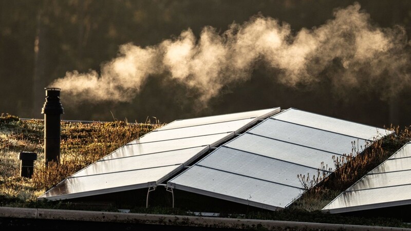 Der Schornstein einer Gastherme für die Heizung und die Warmwasserbereitung dampft am frühen Morgen auf dem Flachdach eines Frankfurter Reihenhauses, auf dem auch eine Solaranlage installiert ist.