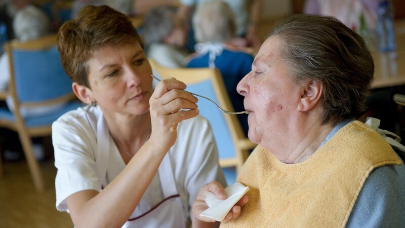 Einer pflegebedürftigen älteren Dame wird das Essen von einer Pflegekraft gegeben. Im Landkreis Cham werden viele Senioren zu Hause von osteurpäischen Pflegerinnen betreut.