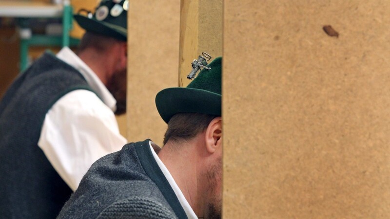 Männer in bayerischer Tracht sitzen in Wahlkabinen. In Bayern sind die Bürger am 15. März zu Kommunalwahlen aufgerufen.