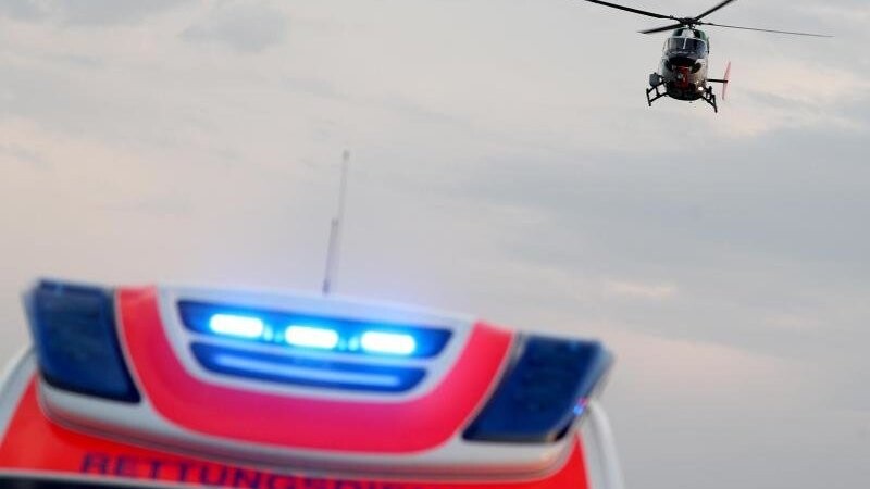 Ein Hubschrauber fliegt über einem Rettungswagen zu einem Unfallort.