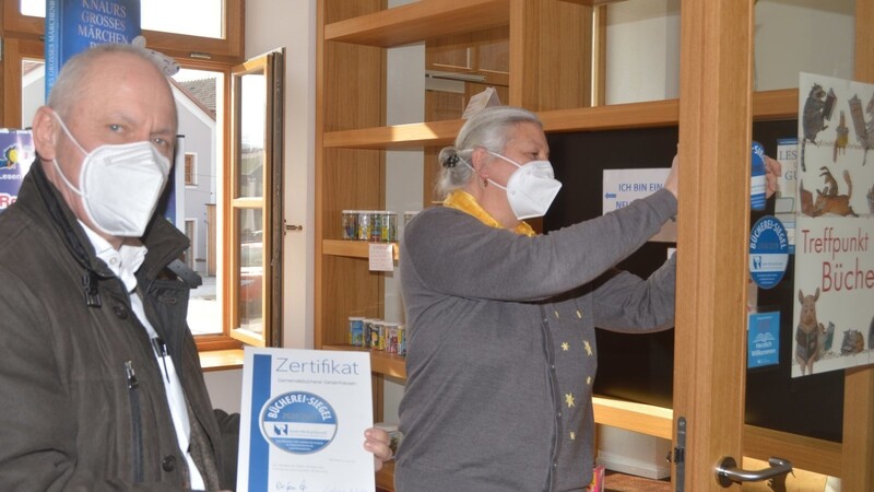 Bürgermeister Josef Reff und Heike Födlmeier, die Leiterin der Gemeindebibliothek, befestigten das silberne Büchereisiegel an der Eingangstür.
