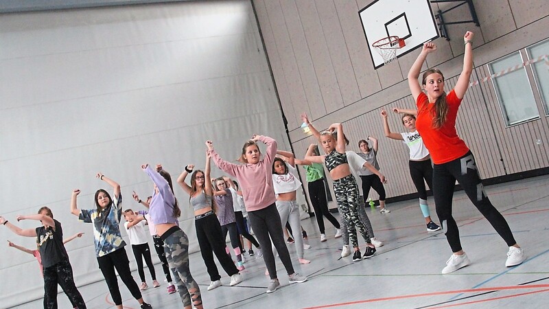 20 Kinder der Hip-Hop-Gruppe des TV Landau bis 14 Jahre schwingen unter der Leitung von Sandra Sänger (vorne rechts) zum Rythmus der Musik die Gliedmaßen. Die bayerische Staatsregierung hofft, dass ein Gutschein mehr Kinder dazu bewegt, in einen Sportverein einzutreten.