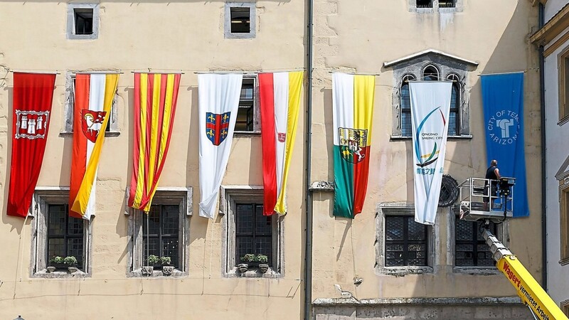 Die Fahnen von Regensburgs Partnerstädten flattern am Alten Rathaus im Wind. Persönliche Kontakte bleiben in diesem Jahr zum großen Teil aus.
