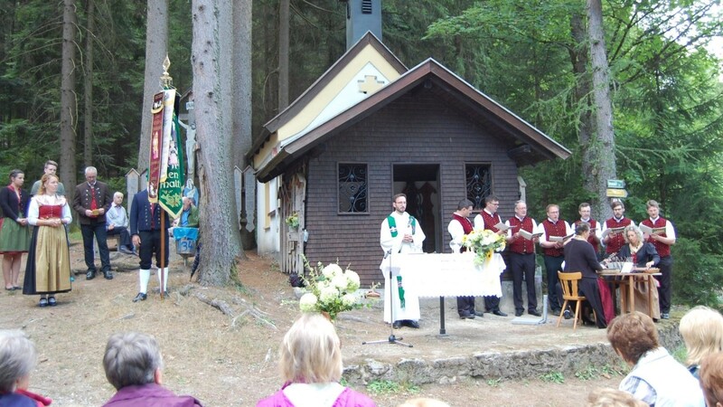 Pater Felix mit den Distelbergsängern und der Waldler Stubnmusi vor der Distelbergkapelle, neben der Vereinsfahne Waldler-Vorstand Hans Greil und Susi Limbeck als Lektorin.