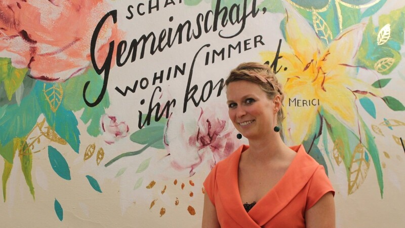 Gudrun Graf vor einer mit einer Kollegin gestalteten farbenfrohen Wand in ihrem Büro.