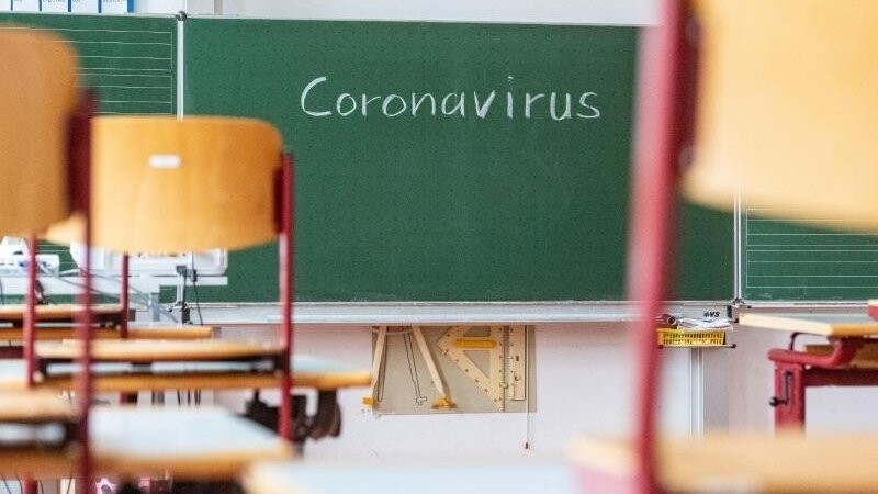 In einem leeren Klassenzimmer steht "Coronavirus" auf der Tafel geschrieben. Foto: Armin Weigel/dpa/Symbolbild