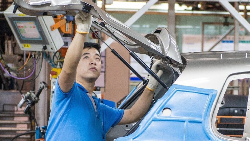 Ein Mitarbeiter bei seiner Arbeit im Werk der Volkswagen AG in Anting bei Shanghai (China) an einem VW Tiguan.