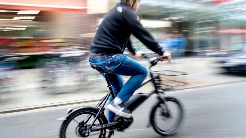 Ein Radfahrer fährt mit einem E-Bike auf einer Straße. Foto: Hauke-Christian Dittrich/dpa/Symbolbild