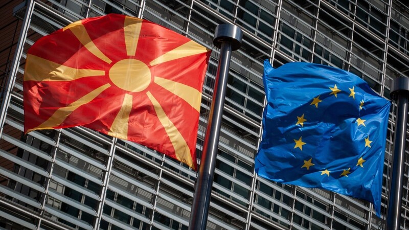 Eine Flagge von Nordmazedonien weht neben einer EU-Flagge im Wind vor dem Berlaymont-Gebäude der EU-Kommission.