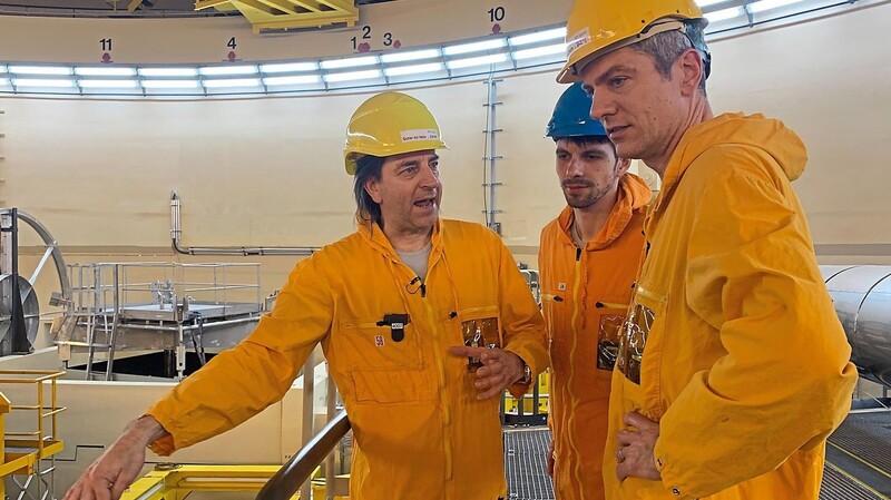 Tagesthemen-Moderator Ingo Zamperoni (r.) und BR-Reporter Philip Kuntschner (Mitte) werden von KKI-Sprecher Bernd Gulich durch das Reaktorgebäude geführt.