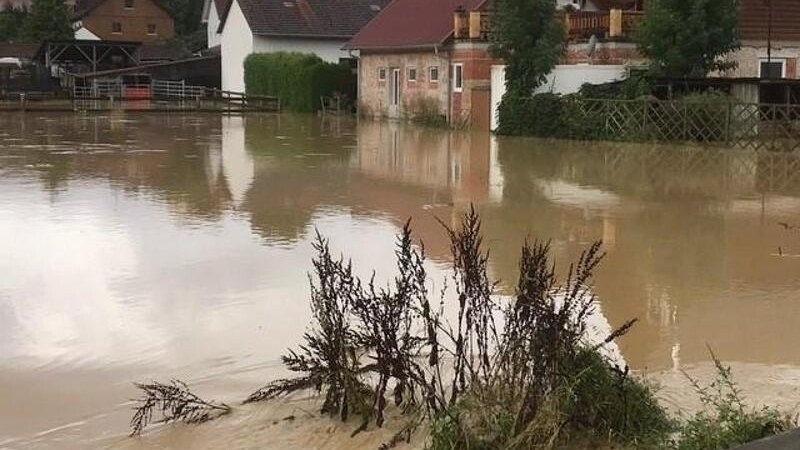 Eine Wiese einer Ortschaft in Oberbayern ist nach starken Regenfällen überschwemmt.