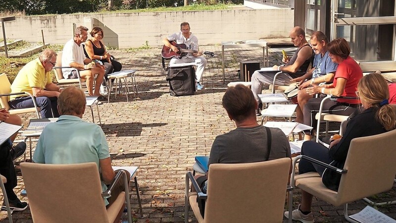 In einem Stuhlkreis sitzen die Teilnehmer der Musiktherapie auf der Patienten-Terrasse des Donau-Isar-Klinikums.