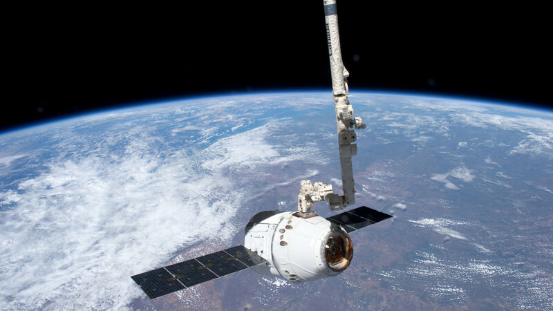 Der kommerzielle Raumfrachter "Dragon" dockt mit Hilfe seines Roboterarms bei einem Testflug im Mai 2012 an der Internationalen Raumstation ISS an. Am Sonntag ist er von seinem ersten richtigen Einsatz von der ISS zurückgekehrt. (Foto: Nasa/Handou)