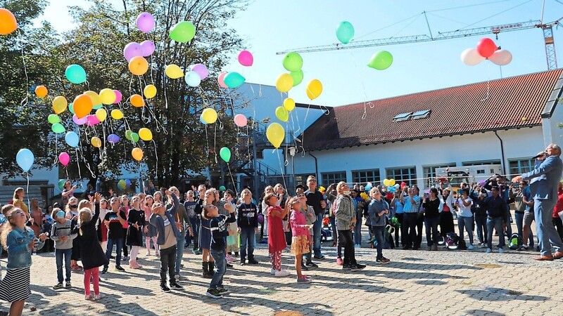Bunte Luftballons steigen in die Luft: Erstklässler, Rektor Michael Prager und Eltern freuen sich über den gelungenen Schuleinstieg.