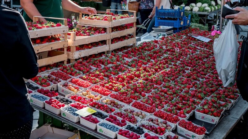 Ein Marktstand verkauft Erdbeeren, Heidelbeeren und Himbeeren.
