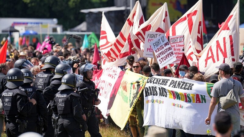 Eine Gruppe Demonstranten steht Polizisten auf der Theresienwiese gegenüber.