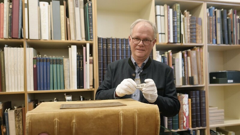 Helmut Hilz zeigt das kleinste und das schwerste Buch der Sammlung. Die wertvollen Exemplare der Bibliothek dürfen nur mit Handschuhen berührt werden.