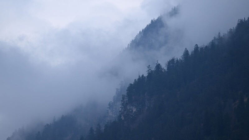 Wolken und Nebel hängt an Berghängen in Farchant in den Bäumen.