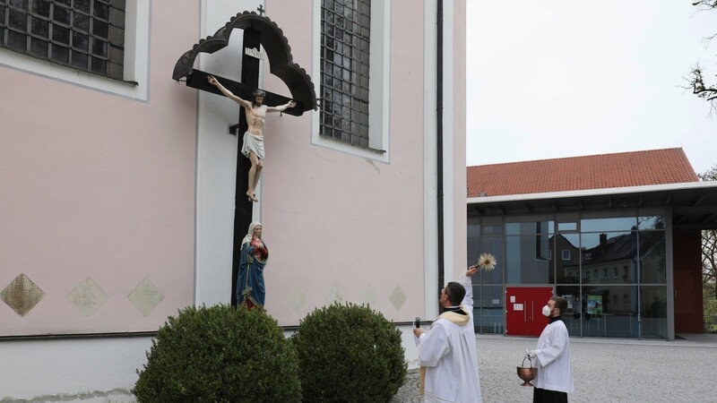 Stadtpfarrer August Lindmeier segnet das wieder an der Südseite der Kirche Sankt Mariä Himmelfahrt aufgestellte Missionskreuz.
