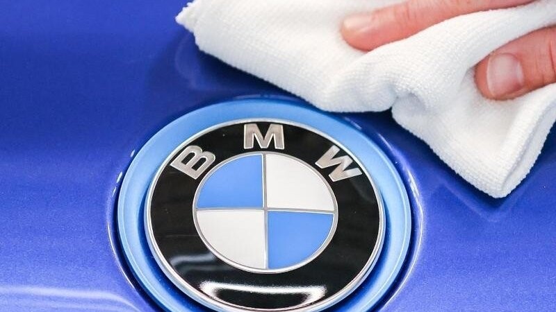 Ein Mitarbeiter von BMW poliert mit einem Tuch das Logo von einem BMW i8. Foto: Jan Woitas/dpa-Zentralbild/dpa/Symbolbild