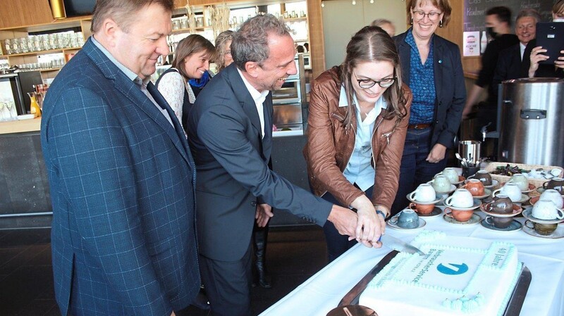Unter den Augen des zweiten Bürgermeisters (links) und von Hauptgeschäftsführerin Ute Mowitz-Rudolph (rechts) schneiden Verbraucherberaterin Nicole Bräu und Minister Glauber die Geburtstagstorte an.