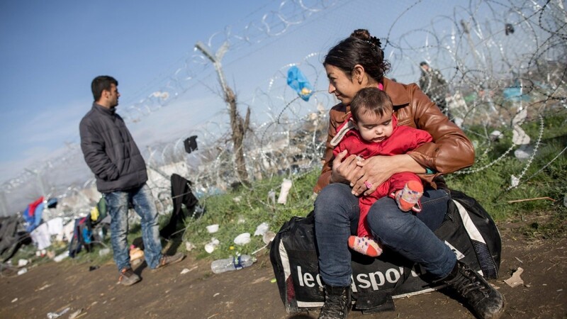 Eine Frau aus Kobani sitz mit ihrem Baby in Ideomeni an der Grenze zwischen Griechenland und Mazedonien direkt am Grenzzaun.
