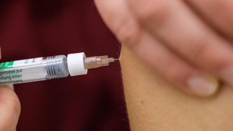 Eine Arzthelferin impft eine Patentin mit einer Spritze.