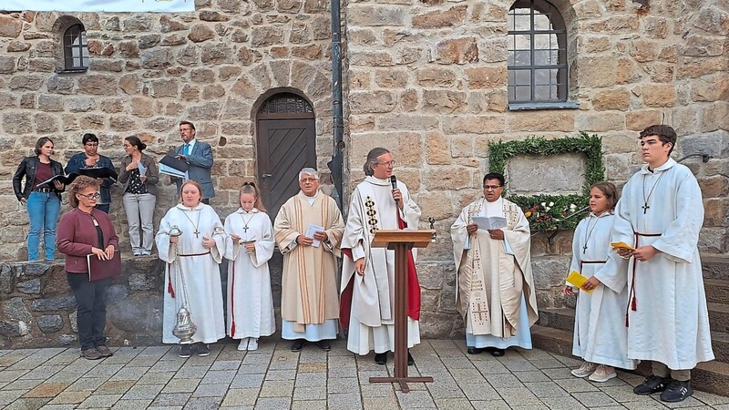 Der Gottesdienst begann vor dem Grundstein. Pfarrer Michael Reißer zusammen mit Diakon Konrad Müller und Pater Joseph, sowie der Schola, den Ministranten und der Lektorin.