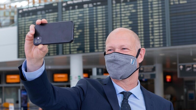 Jost Lammers, Vorsitzender der Geschäftsführung der Flughafen München GmbH beim Selfie vor voller Anzeigentafel.