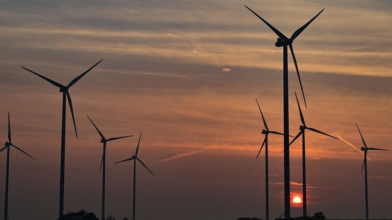 Windenergieanlagen sind im Sonnenuntergang zu sehen.