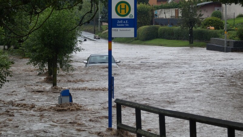 Ein Fahrzeug ist auf einer überfluteten Straße von Hochwasser umgeben.