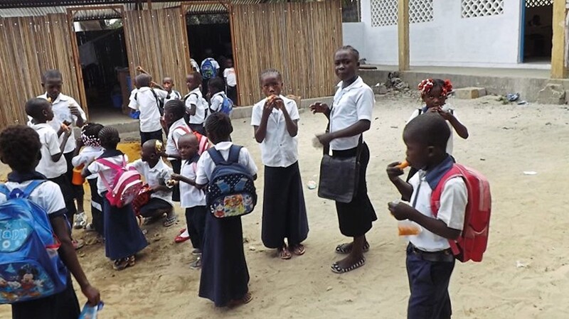 Kinder in Schuluniform vor der Schule.