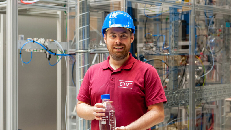 Prof. Jakob Burger hat die OME-Anlage in Straubing errichtet und hält eine Flasche mit dem Endprodukt in Händen.
