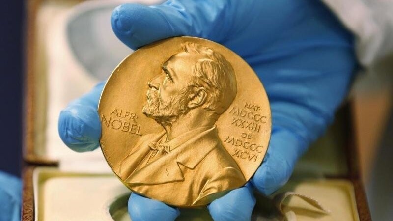 Ein Mitarbeiter der Nationalbibliothek zeigt eine goldene Nobelpreismedaille.