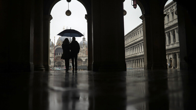 Ein Paar schützt sich auf dem Markusplatz in Venedig mit einem Regenschirmen vor dem Regen. Die italienischen Tourismusbehörden befürchten, dass das Coronavirus ihrer Branche mehr Schaden zufügen könnte als die Terroranschläge vom 11. September.