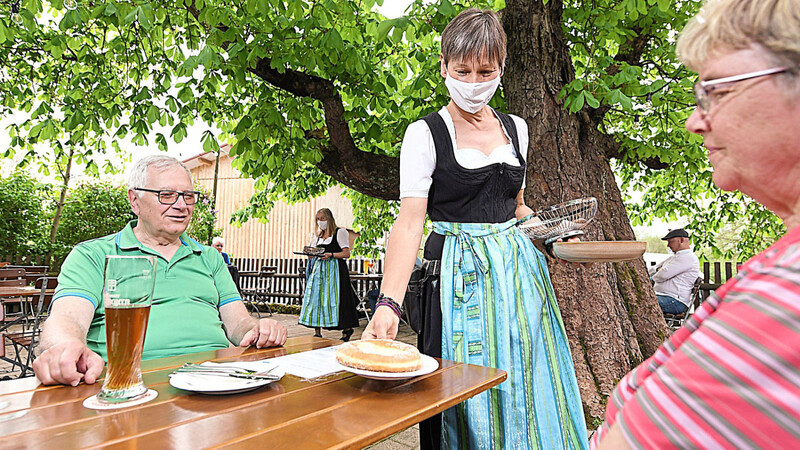 Eine Kellnerin mit Mund-Nasen-Schutz bedient im Biergarten. Das könnte bald auch wieder im Landkreis Regensburg möglich sein.
