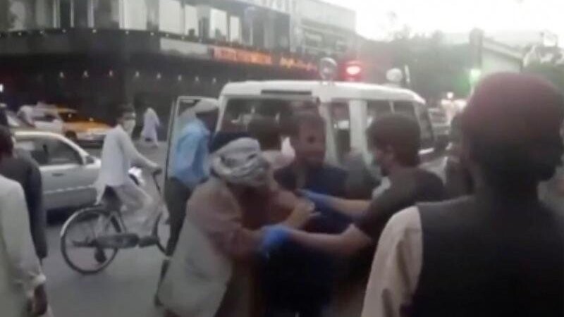Menschen kümmern sich um eine verwundete Person in der Nähe der Explosion außerhalb des Flughafens in Kabul.