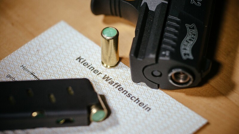 Ein Kleiner Waffenschein liegt zwischen einer Schreckschuss-Pistole "Walther P22", einem Magazin und einer Knallpatrone. Das Dokument berechtigt den Besitzer zum Tragen einer solchen Waffe in der Öffentlichkeit.