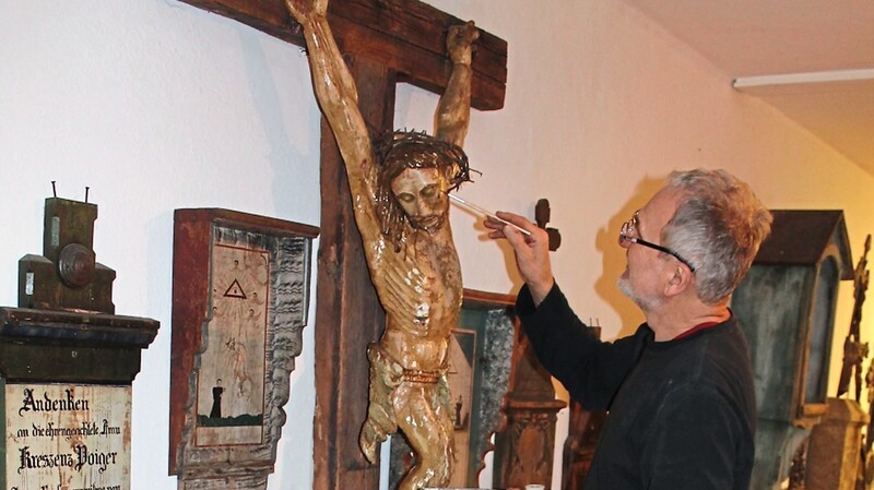 Restaurator Alfons Empl befestigte die abgeblätterte Fassung des barocken Christus. Das Kruzifix von Anfang des 19. Jahrhunderts stammt aus Landasberg.