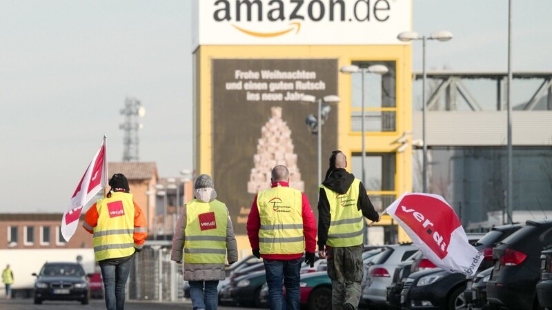 Streikende Mitarbeiter gehen vor der Betriebsstätte des Online-Händlers Amazon.