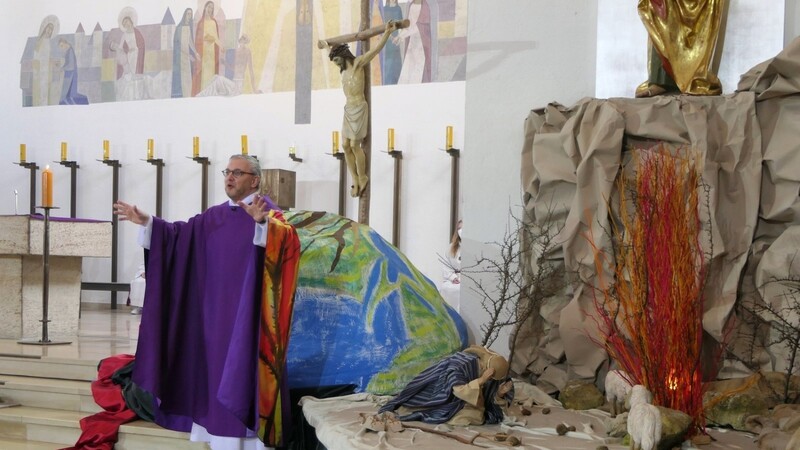 Dekan Johannes Plank bei seiner Predigt vor der Weltkugel mit dem Kreuz und dem brennenden Dornbusch mit dem knienden Mose.
