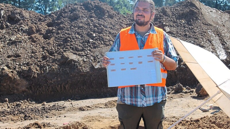 Archäologe Tobias Riegg mit einer Zeichnung im Profil der Ausgrabungen .