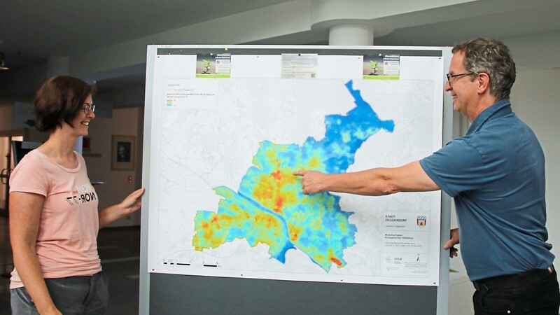 Die städtische Umweltbeauftragte Ulrike Watzek und Stadtplaner Klaus Busch vor einer Karte, die veranschaulicht, welche Bereiche der Stadt Deggendorf sich besonders stark aufheizen.