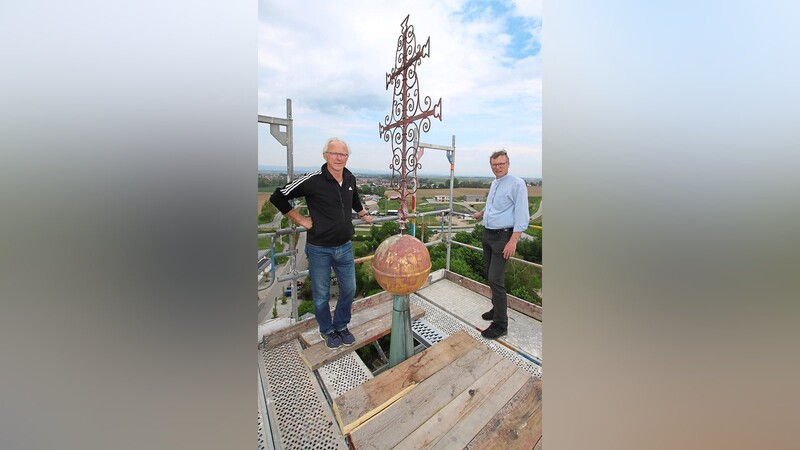 Pfarrer Markus Daschner (rechts) und Kirchenpfleger Bernhard Gebhard (links) nehmen das Turmkreuz vor der Abnahme in Augenschein. Leider wurde keine Zeitkapsel, die Aufschluss über den Zeitpunkt der letzten Sanierung geben würde, gefunden.