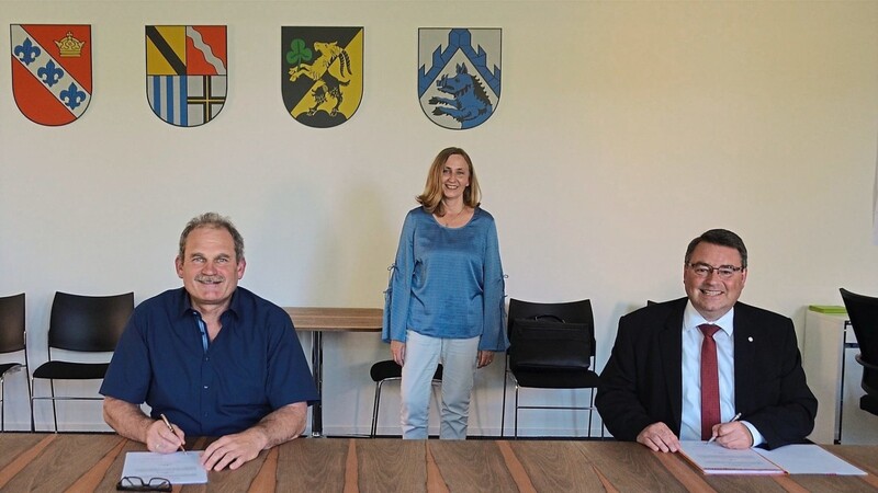 Bürgermeister Toni Schmid (l.) und Regionalvorstand Martin Steinkirchner (r.) unterzeichnen den Vertrag zur Trägerschaft; mit im Bild ist Sachgebietsleiterin Sylvia Meyer (Mitte).