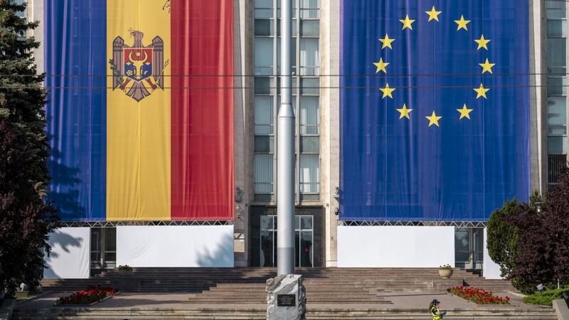 Eine Frau läuft am Regierungsgebäude vorbei, das mit den Flaggen der Europäischen Union und der Republik Moldau geschmückt ist. Die hochkarätige Gästeliste verspricht die dringend gewünschte Aufmerksamkeit.