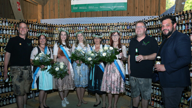 Bierfestkönigin (4.v.li.) vier Prinzessinnen und die Vorsitzenden Stefan Seitz (links) und Christian Wild (2. von rechts) sowie Bürgermeister Raffael Parzefall vor dem Bierregal das alle angebotenen Sorten zeigt.