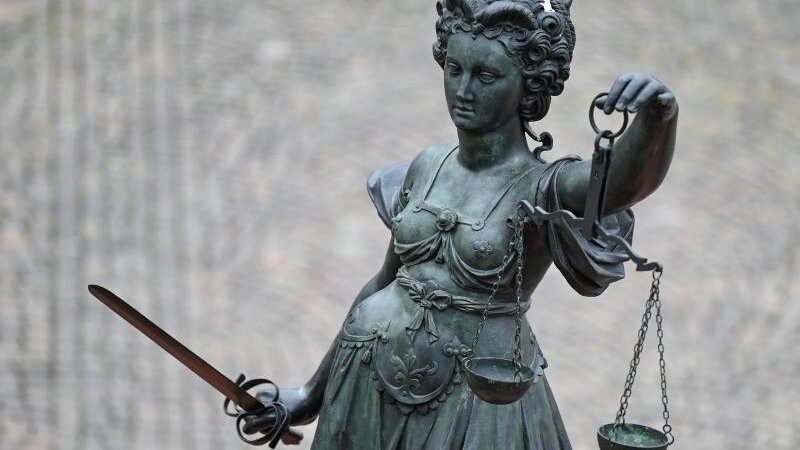 Eine Statue der Justitia hält eine Waage und ein Schwert in der Hand.
