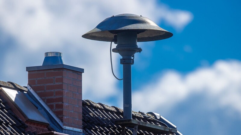 Eine Alarmsirene steht auf einem Hausdach. Lautsprecherdurchsagen oder Mitteilungen über Warn-Apps sind weitere Warnmöglichkeiten.